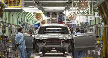 Varios trabajadores de la planta de pintura de Ford en Almussafes (Valencia), revisan una carrocer&iacute;a tras su paso por la zona de pintura. 