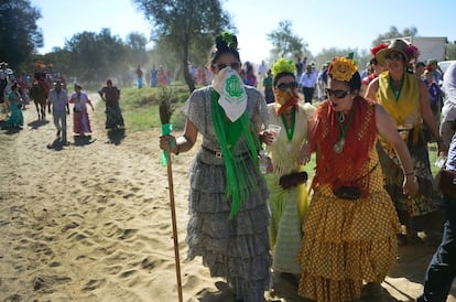 Las romeras se tapan la boca para evitar el polvo del camino mientras cruzan el puente de Ajoli, en la aldea del Rocío.