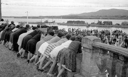 Foz (Lugo), 1 de septiembre de 1960. Muchachas observando desde el muro el ambiente de la fiesta del pueblo.