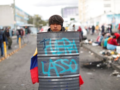 Cesar llumiquinga posa con un escudo de chapa con la pintada "Fuera Lasso" este domingo en Quito.