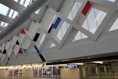 La celosía del vestíbulo de la terminal de llegadas de Atocha rompe la uniformidad blanca con figuras geométricas rojas, negras y azules. Es una obra, 'La llegada, 2010', del artista argentino César Paternosto.