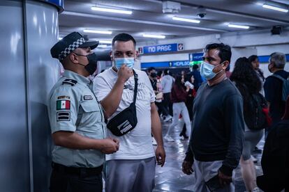 Viajeros hablan con un elemento de la Guardia Nacional en la estación Hidalgo.