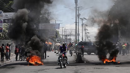 Motorists pass by a burning barricade during a protest as the government said it would extend a state of emergency for another month, in Port-au-Prince, Haiti, March 7, 2024.