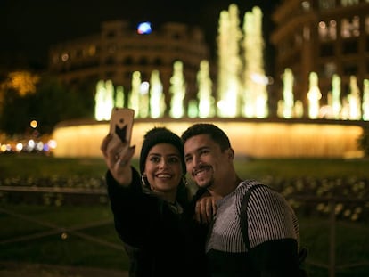 Una pareja se fotograf&iacute;a ante las fuentes gemelas de Plaza Catalu&ntilde;a, en Barcelona, iluminadas de amarillo en solidaridad con los presos.