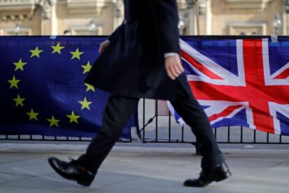 Un hombre pasa delante de las banderas de los manifestantes contra el Brexit frente a las Casas del Parlamento, en Londres. La Primera Ministra británica, Theresa May, ha pedido este martes a los parlamentarios que le den más tiempo para conversar con la Unión Europea sobre la renegociación del Brexit, unas semanas antes de la fecha de salida, programada para el 29 de marzo. 