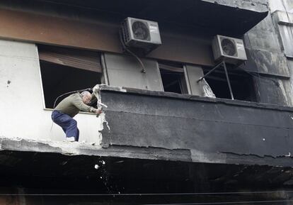 Un hombre trabaja en la fachada de una casa quemada en Homs.