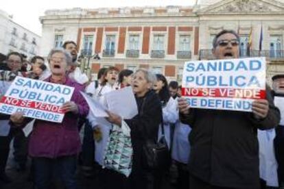 Decenas de personas participan en un concierto de villancicos organizado por la Plataforma contra la privatización de los centros de Atención Primaria, ante la sede del Gobierno regional de la Puerta del Sol.