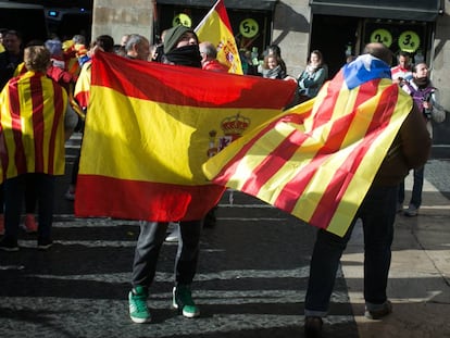 Un ciutadà amb una bandera estelada penjada al coll creua la plaça Sant Jaume, a Barcelona, amb banderes espanyoles el 6 de desembre.