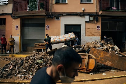 Dos personas sacan un colchón de una vivienda afectada por la riada, este lunes en Benetússer.