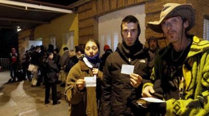 Tres ciudadanos con sus cartillas para cenar, en el comedor de la Casa de Campo de Madrid.