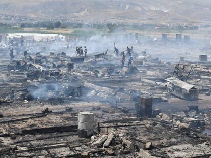 Miembros de Protecci&oacute;n Civil y civiles apagan los rescoldos del fuego que ha arrasado un campo de refugiados del valle de la Bekaa. 