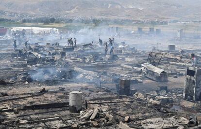 Miembros de Protecci&oacute;n Civil y civiles apagan los rescoldos del fuego que ha arrasado un campo de refugiados del valle de la Bekaa. 