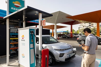 Un hombre carga su coche eléctrico en un punto de recarga situado en una gasolinera Repsol, en una imagen cedida por la empresa.