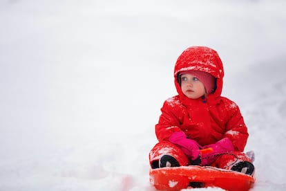 Un niño juega con su trineo en la nieve.