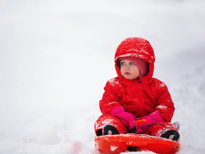 Un niño juega con su trineo en la nieve.