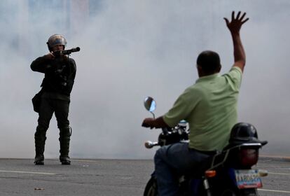 Un hombre en una moto levanta sus brazos frente a un oficial de la Guardia Nacional Bolivariana (GNB), durante una manifestación en Caracas.