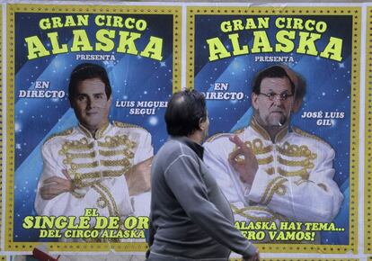 Un hombre toma una fotografía de los cárteles de un circo que actúa estos días en Valencia y en los que alguien ha sustituido las caras de dos de sus artistas por los candidatos a la presidencia del Gobierno Albert Rivera y Mariano Rajoy.