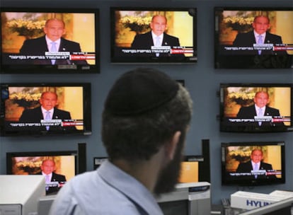 Un hombre sigue la declaración de Olmert en Jerusalén.