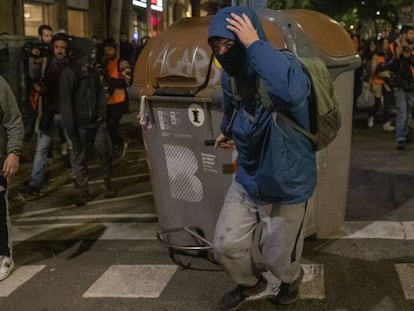 Un encapuchado arrastra un contenedor en Barcelona.