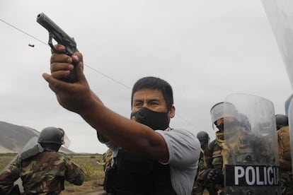 Un miembro de la Policía peruana apunta su arma a manifestantes, el miércoles durante una protesta de trabajadores agroindustriales.