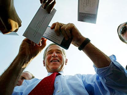 George W. Bush firma autógrafos durante su visita de campaña a una fábrica.