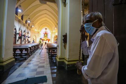 Un hombre con mascarilla hace sonar la campana en el inicio del domingo de Pascua en Colombo.