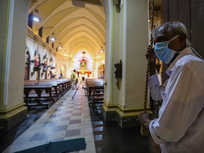 Un hombre con mascarilla hace sonar la campana en el inicio del domingo de Pascua en Colombo.