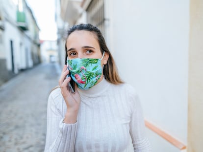 Una mujer con mascarilla habla por teléfono.