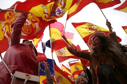 Manifestantes ondean banderas de España durante la lectura de los discursos, en la plaza de Colón de Madrid.