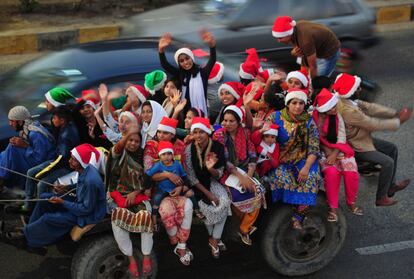 Un grupo de pakistaníes con sombreros de Papá Noel se dirige a ver una competición de camellos, en Karachi (Pakistán).