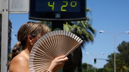Una mujer se abanica mientras pasa por un termómetro de calle en Córdoba.