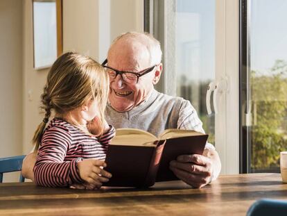 Un abuelo disfruta leyendo con su nieta.