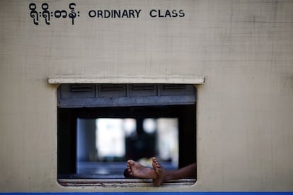 Los pies de un hombre asoman por la ventanilla de un tren estacionado en Naypyidaw, Myanmar.