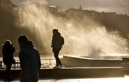 Dos mujeres toman fotografías de las olas saltando en el Puerto Viejo de Getxo (Bizkaia) este miércoles.