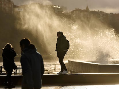 Dos mujeres toman fotografías de las olas saltando en el Puerto Viejo de Getxo (Bizkaia) este miércoles.
