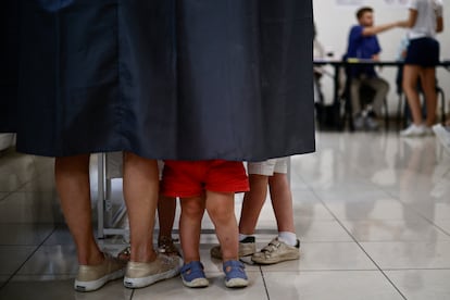 Una mujer y sus hijos se encuentran en una mesa electoral para votar en la segunda vuelta de las elecciones parlamentarias francesas tempranas,en París.