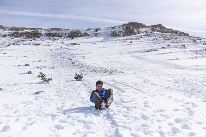 Varios niños refugiados sirios juegan lanzándose sobre bolsas de plástico en la nieve por las montañas que separan Líbano de Siria.