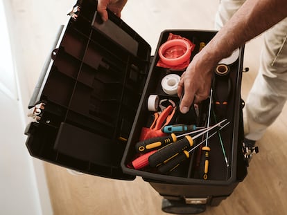 Una mano abriendo la caja de herramientas con ruedas