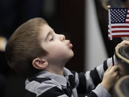 Un niño juega con una bandera de EE UU durante la ceremonia de naturalización de su madre. 