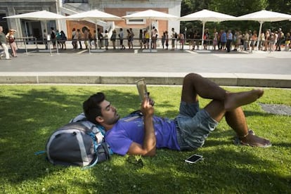 A tourist takes a break while people stand in line outside the Prado museum.