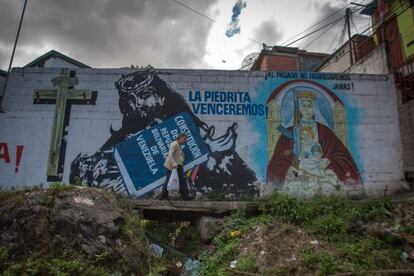 Un hombre camina frente a una pared con mensajes de apoyo al presidente Hugo Ch&aacute;vez.