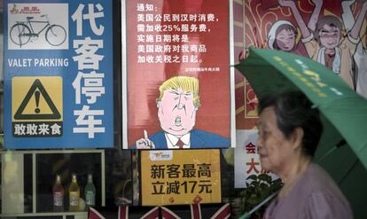 Una mujer pasa junto a un póster que caricaturiza a Trump, en Guangzhou.