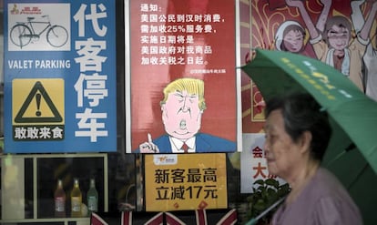 Una mujer pasa junto a un póster que caricaturiza a Trump, en Guangzhou.