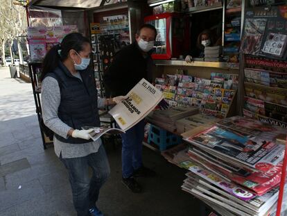 Una mujer compra un periódico, en un quiosco de la calle Toledo, en Madrid, el 15 de marzo.