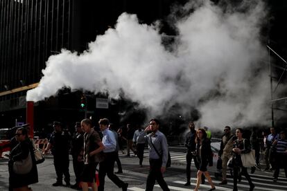 Una nube de huno se eleva sobre el paso de los transeuntes en la calle 56 de Manhattan, en Nueva York (EE UU).