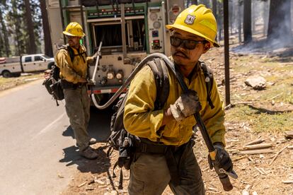 El bombero Matt Shibuya y el asistente operador John Carter del Servicio Forestal de Cleveland sacan una manguera para humedecer los puntos calientes que van surgiendo, evitando que se prendan en llamas, este 11 de julio.