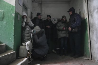 Un grupo de ciudadanos ucranios se protegen de los bombardeos en la entrada de un edificio de apartamentos en Mariupol, el domingo.