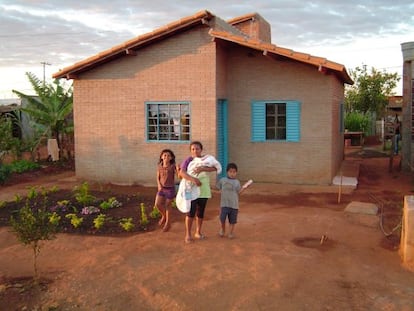 Fam&iacute;lia em frente &agrave; casa constru&iacute;da pelo projeto A&ccedil;&atilde;o Moradia.