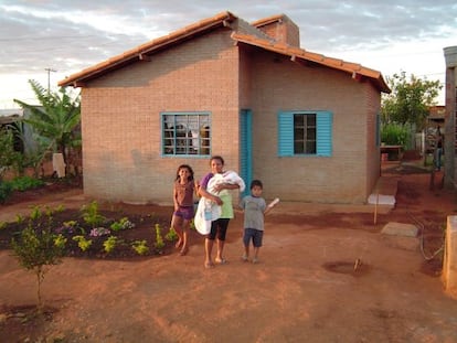 Fam&iacute;lia em frente &agrave; casa constru&iacute;da pelo projeto A&ccedil;&atilde;o Moradia.