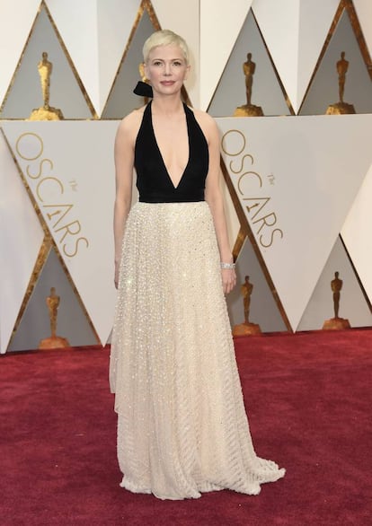 A la actriz de <i>Manchester frente al mar</i>, que estaba nominada por cuarta vez, se le da bien la alfombra roja de los Oscar. Se estrenó con su memorable Vera Wang color mostaza cuando acudió con su entonces pareja Heath Ledger por Brokeback Mountain; llevó un Chanel blanco de pedrería en 2011, cuando optaba al premio por Blue Valentine, y un Louis Vuitton rojo en 2012, cuando concursaba por su retrato de Marilyn Monroe. Este año optó por un sobrio traje negro y blanco roto.